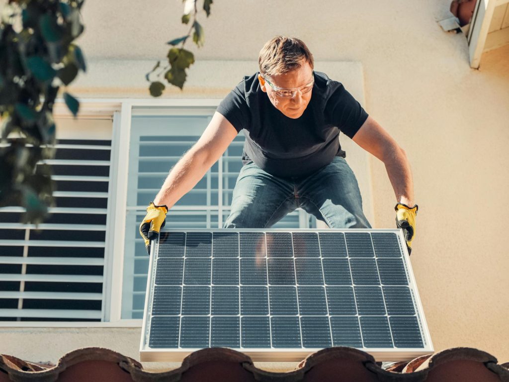 Man installing a solar panel on a house, symbolizing a solar panel transfer