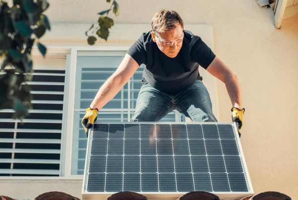 Man installing a solar panel on a house, symbolizing a solar panel transfer