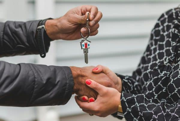 A man handing a woman a house key, symbolizing real estate deals