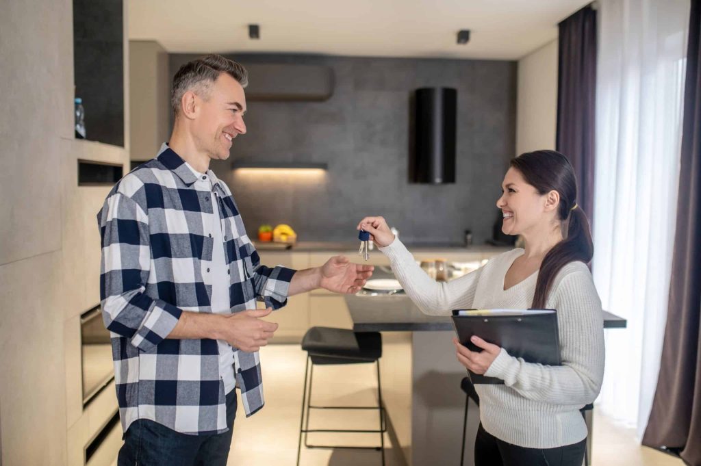 Man receiving keys from realtor indoors.