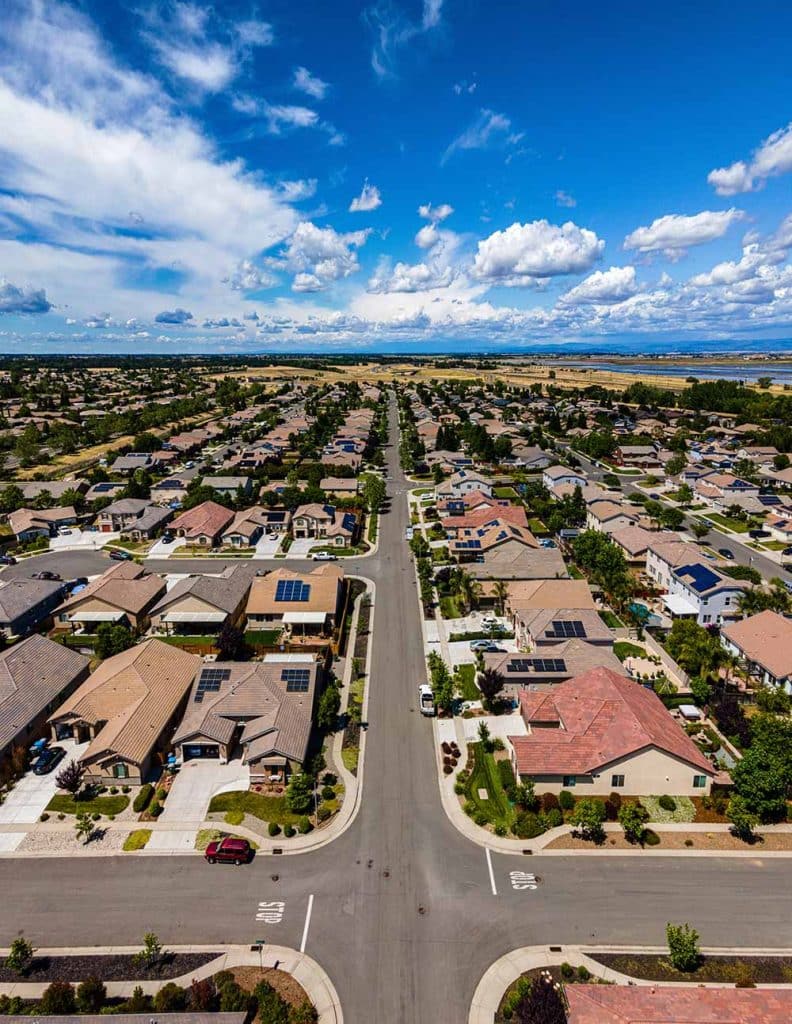 An aerial view of a suburban neighborhood with many houses and two "STOP" signs on the street.