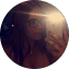 A woman with glasses and dark hair holds a phone, its flash reflecting brightly on her face.